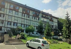 a white car parked in front of a large building at Garsoniera Flori - Sinaia in Sinaia