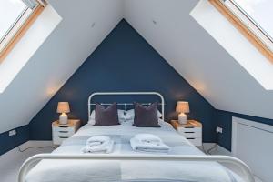a bedroom with a bed with a blue wall at Holmwood by Keepers Cottages in Walmer