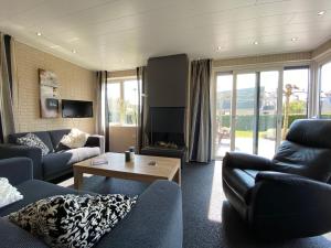a living room with blue couches and a table at Luxe vakantiewoning met stoomcabine en bubbelbad in Tzummarum