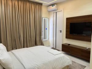 a bedroom with a bed and a flat screen tv at Cozy, Serene Ambiance With Nice Balcony Views in Ikate +34 photos