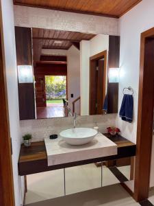 a bathroom with a sink and a large mirror at Casa espaçosa na Guarda do Embaú in Palhoça