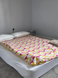 a bed with a colorful blanket on top of it at Stay Near Colchester twn centre3 in Hythe