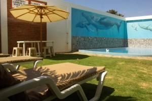 a pool with a table and chairs and an umbrella at Hotel Rupay Wasi in Los Órganos
