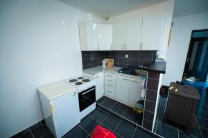 a small kitchen with white cabinets and a black tile floor at Villa Mostanica, Kozarska Dubica in Gornjoselci