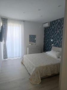 ein weißes Schlafzimmer mit einem Bett und einem Fenster in der Unterkunft Maison Martina in Giardini-Naxos