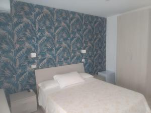 ein Schlafzimmer mit einem Bett und einer Tapete in der Unterkunft Maison Martina in Giardini-Naxos
