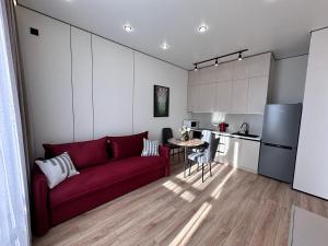 a living room with a red couch and a kitchen at Уютная квартира в ЖК Республика in Astana
