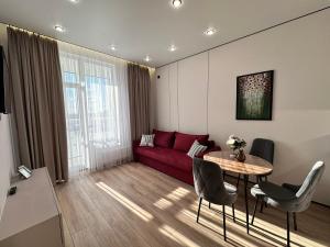 a living room with a red couch and a table at Уютная квартира в ЖК Республика in Astana