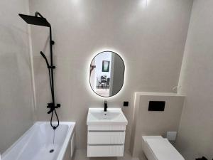 a white bathroom with a sink and a mirror at Уютная квартира в ЖК Республика in Astana +4 photos