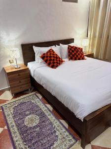 ein Bett mit zwei Kissen darauf mit einem Nachttisch in der Unterkunft Top7dBASMALA 1 in Salé