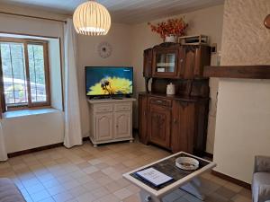 a living room with a flat screen tv on a cabinet at Les VIGNEAUX Hautes Alpes, Appartement 4 personnes, avec belle terrasse panoramique in Les Vigneaux