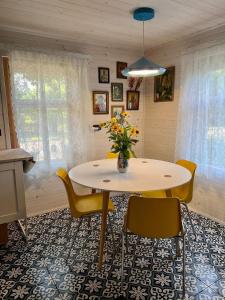 a dining room table with yellow chairs and a vase of flowers at Jak u babci na wsi in Siemichocze +127 photos