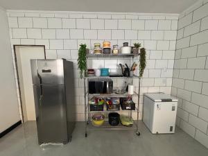 a kitchen with a refrigerator and a shelf with food at A Casa Azul in Peruíbe
