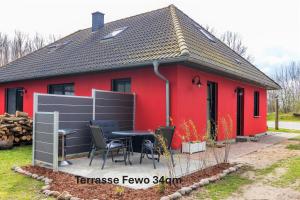 a red house with a table and chairs in front of it at Ferienhaus Am Pappelwald in Glowe