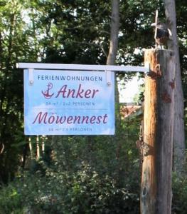 a sign hanging on a wooden pole next to a tree at Ferienhaus Am Pappelwald in Glowe