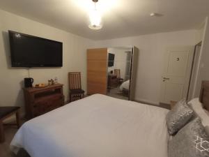 a bedroom with a white bed and a flat screen tv at The Paddock Side in Uttoxeter