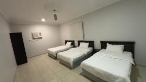 two beds in a hotel room with white walls at شقق النورس in Rayyis