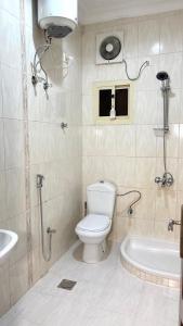 a bathroom with a toilet and a tub and a sink at شقق النورس in Rayyis +21 photos