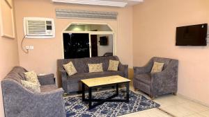 a living room with a couch and two chairs and a table at شقق النورس in Rayyis