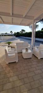 a patio with white chairs and tables on a patio at Podilimbo - Ilios e Thalassa in Paestum