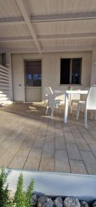 a patio with a white table and chairs on a deck at Podilimbo - Ilios e Thalassa in Paestum