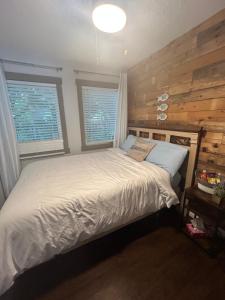 a bedroom with a white bed with two windows at Cozy cottage by the beach in Pointe-du-Chêne
