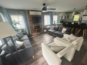 a living room with two couches and a kitchen at Cozy cottage by the beach in Pointe-du-Chêne +27 photos