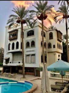 a building with palm trees in front of a swimming pool at Villa in El-Manâkh