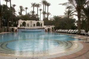 a large swimming pool with chairs and a building at Villa in El-Manâkh