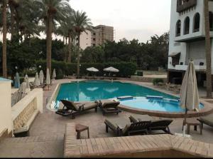 a swimming pool with chairs and umbrellas next to a building at Villa in El-Manâkh