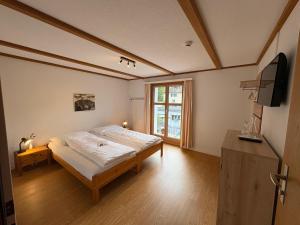 a bedroom with a bed and a television in it at Garni Sternen in Obstalden