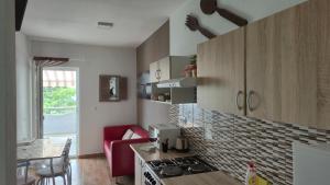 a kitchen with a stove and a red couch in it at Apartman Bilandžić Drage in Drage