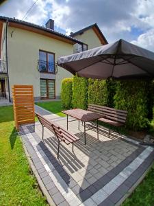 a picnic table with an umbrella and two benches at Agroturystyka u Krzysztofa ZATOR ,ENERGYLANDIA , NOCLEGI in Graboszyce