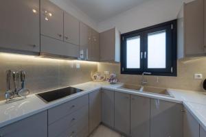 a kitchen with white cabinets and a sink and a window at Marios Suite Corfu in Corfu