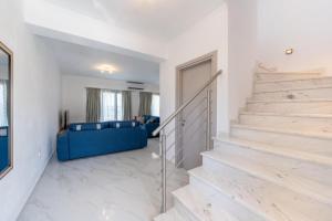 a white living room with stairs and a blue couch at Marios Suite Corfu in Corfu