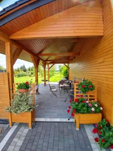 a wooden pavilion with two benches and flowers at Agroturystyka u Krzysztofa ZATOR ,ENERGYLANDIA , NOCLEGI in Graboszyce