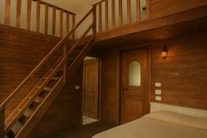 a bedroom with a wooden staircase and a bed at La Râu - Căsuța de sus in Cîmpulung