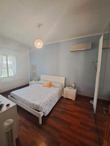 a bedroom with a white bed and a wooden floor at The Shell in Vallecrosia