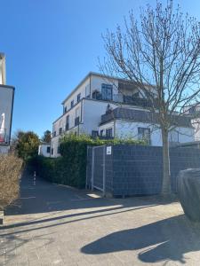 a white building with a tree and a fence at Traumwohnung im Kölner Süden in Hürth