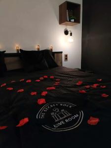 a bed with a black blanket with red flowers on it at Secret Rock - Jaccuzi privé in La-Roche-en-Ardenne