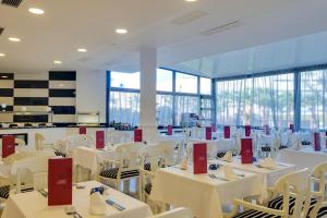 a dining room with white tables and chairs and windows at Cala Millor Garden Hotel - Adults Only in Cala Millor