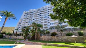 a large apartment building with palm trees and a swimming pool at Benidorm Ambra in Villajoyosa