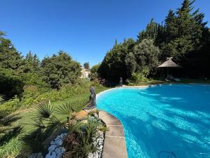 a swimming pool with a statue next to a resort at MAS PROVENCAL A FLANC DE COLLINE in Bollène