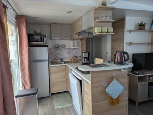 eine kleine Küche mit weißen Geräten und Holzschränken in der Unterkunft Mobil home Apollon Riviera in Saint-Papoul