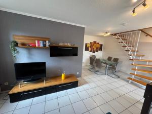 a living room with a tv and a table and a staircase at FeWo Stadt-Domizil Rietberg für 6 Pers mit Parkplatz in Rietberg