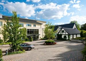 a house with a car parked in the driveway at Landhotel Krummenweg in Ratingen