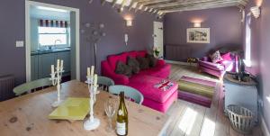 ein Wohnzimmer mit einem rosa Sofa und einem Tisch in der Unterkunft Waterfront Cottage in Aldeburgh