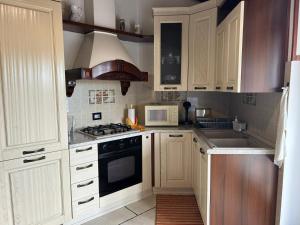 a kitchen with white cabinets and a stove and a microwave at MXP apartment, shuttle service, parking free in Cardano al Campo
