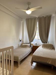 a bedroom with two beds and a ceiling fan at La casa de la Brisa in Piles