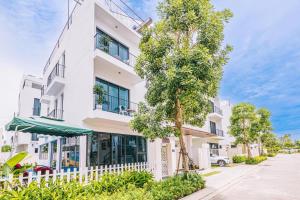 a white building with a tree in front of it at Moonlight Villa Vlasta Sam Son in Thanh Hóa